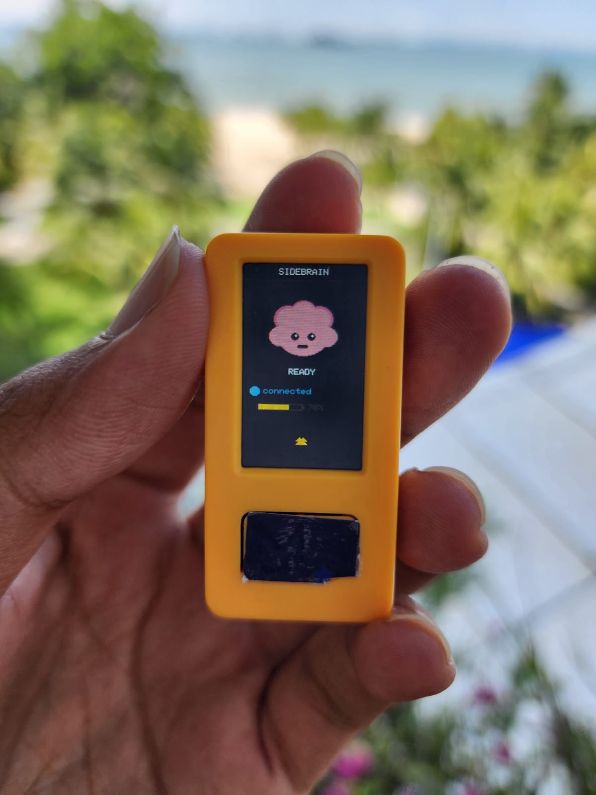 Hand holding the Sidebrain wearable voice pin with READY status on screen