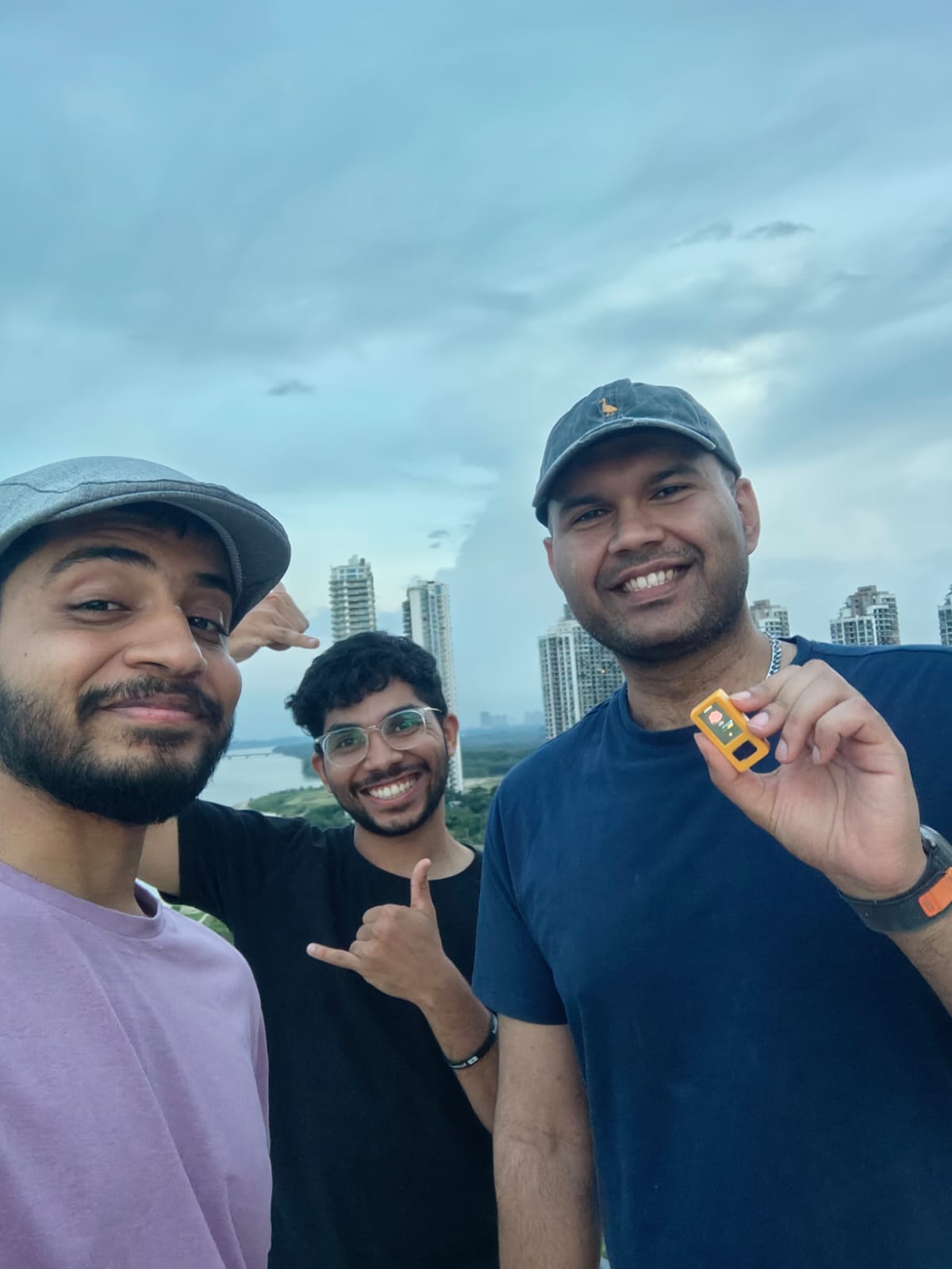 Team members holding the Sidebrain pin outdoors with city skyline in background